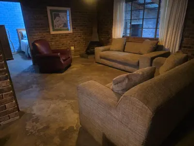 a living room with couches and a brick wall at Treeferns Trout Lodge in Dullstroom