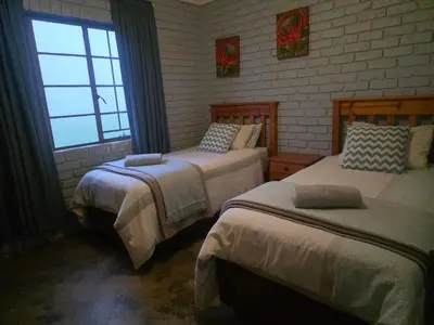 a bedroom with two beds and a window at Treeferns Trout Lodge in Dullstroom
