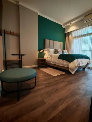 a bedroom with a bed and a green wall at Menlyn Maine Trilogy Apartment 1316 & 1316A in Pretoria