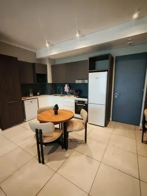 a kitchen with a table and chairs and a refrigerator at Menlyn Maine Trilogy Apartment 1316 & 1316A in Pretoria