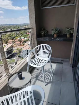 a balcony with a white chair and a table at Menlyn Maine Trilogy Apartment 1316 & 1316A in Pretoria
