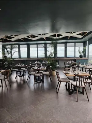 a dining room with tables and chairs and windows at Menlyn Maine Trilogy Apartment 1316 & 1316A in Pretoria
