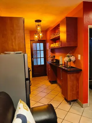 a kitchen with orange walls and a black counter top at Express at Urban Cove in Nelspruit