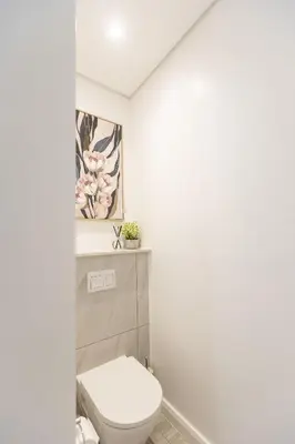 a white bathroom with a toilet and flowers on the wall at 932 menlyn maine in Pretoria