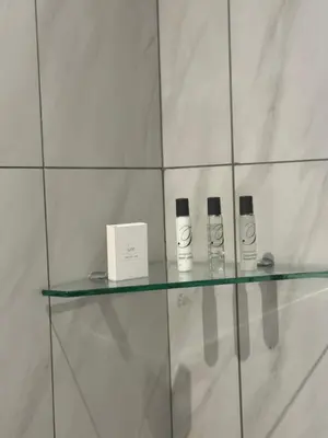 a glass shelf with two bottles and a box on it at 932 menlyn maine in Pretoria