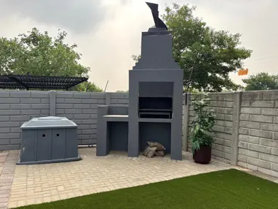 a barbecue grill in a backyard next to a fence at 1 on Brandspruit in Secunda