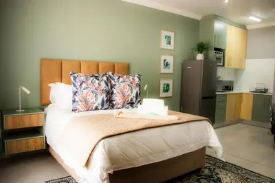 a bedroom with a large bed and a kitchen at 1 on Brandspruit in Secunda