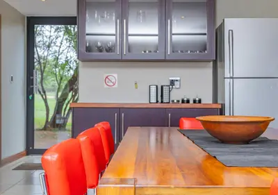 a kitchen with a wooden table with orange chairs and a refrigerator at Bush Lodge Zebula 82 - 2 x 2B Chalets in Warmbaths