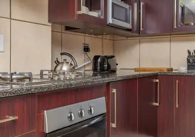 a kitchen with wooden cabinets and a stainless steel stove at Bush Lodge Zebula 82 - 2 x 2B Chalets in Warmbaths