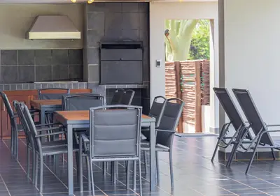 a dining room with tables and chairs and a stove at Bush Lodge Zebula 82 - 2 x 2B Chalets in Warmbaths