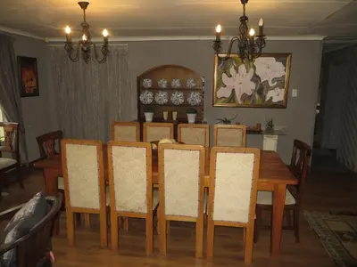 a dining room table with chairs and a wooden table at Dandelion Cottage in Boschkop