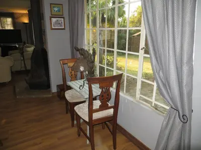 a dining room table and chairs in front of a window at Dandelion Cottage in Boschkop