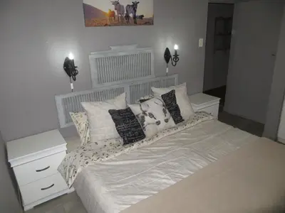 a bedroom with a large bed with pillows on it at Dandelion Cottage in Boschkop