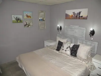 a bedroom with a bed with pillows and pictures on the wall at Dandelion Cottage in Boschkop