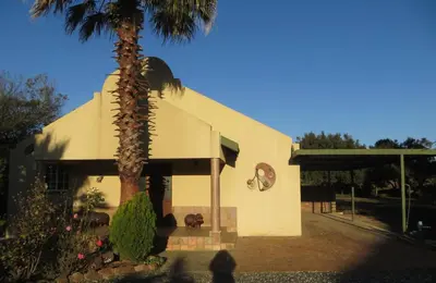 a building with a palm tree in front of it at Dandelion Cottage in Boschkop