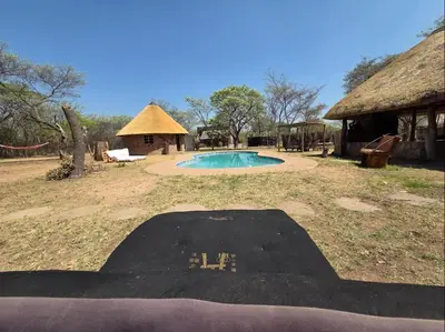 a swimming pool in front of a house with a hut at LoWes Africa in Vaalwater