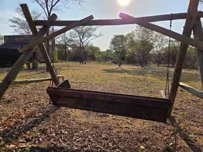 a wooden swing in a field with a fence at LoWes Africa in Vaalwater