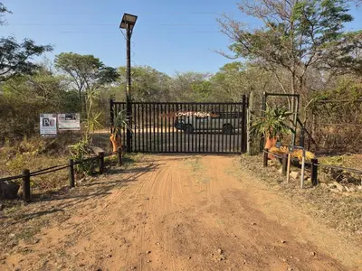 a gate with a bus behind it on a dirt road at LoWes Africa in Vaalwater