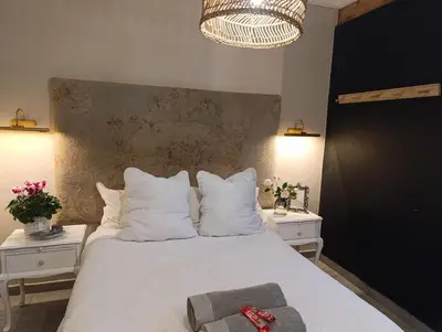a bedroom with a white bed with two white night stands at Net 'n Bed in Middelburg