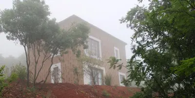 a building on a hill with trees in front of it at Oppiberg Cottage with River View in Hartbeespoort