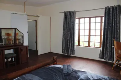 a bedroom with a bed and a large window at Oppiberg Cottage with River View in Hartbeespoort