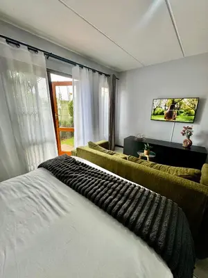 a bedroom with a bed and a couch and a tv at Protea Apartment Midrand in Midrand