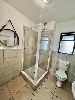 a bathroom with a shower with a toilet and a mirror at Protea Apartment Midrand in Midrand