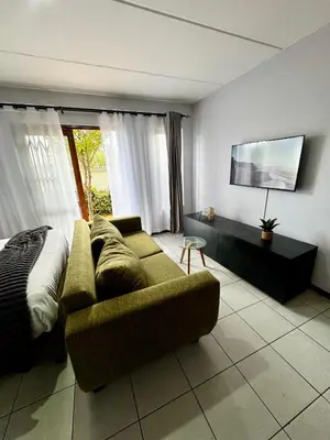 a living room with a couch and a bed at Protea Apartment Midrand in Midrand