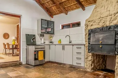 a kitchen with white cabinets and a stone wall at Refresh On Wolseley in Secunda