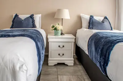 a bedroom with two beds and a night stand with a lamp at Refresh On Wolseley in Secunda