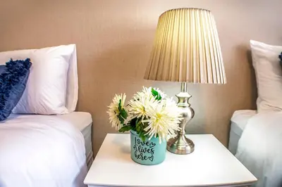 a table with a lamp and a vase with flowers on it at Refresh On Wolseley in Secunda