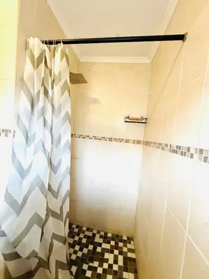 a bathroom with a shower with a checkered floor at Refresh On Wolseley in Secunda