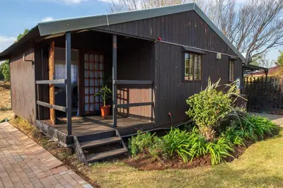 a small black house with a porch and stairs at Farmstay at Rehoboth in Benoni