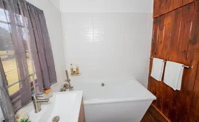 a bathroom with a white tub and a sink and a window at Farmstay at Rehoboth in Benoni