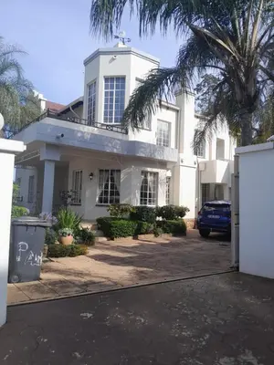 a white house with a palm tree and a blue car at Prins Albert 6 in Pretoria