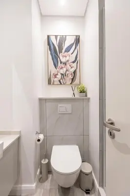 a bathroom with a toilet and a painting on the wall at 132 Menlyn Maine in Pretoria