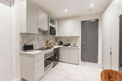 a kitchen with white cabinets and a washer at 132 Menlyn Maine in Pretoria
