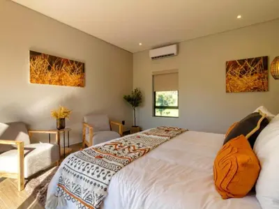 a bedroom with a large white bed and a chair at Tenkudu Bush Lodge in Hammanskraal