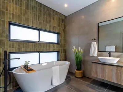 a bathroom with a tub and a sink and a mirror at Tenkudu Bush Lodge in Hammanskraal