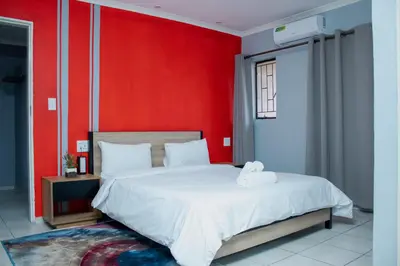 a bedroom with a large bed with a red wall at No 419 Guest House in Midrand