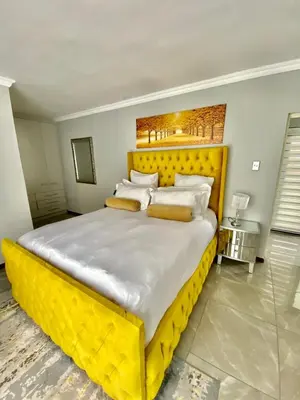 a large bed with a yellow headboard in a bedroom at Alimu villa in Nelspruit