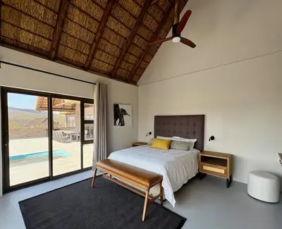 a bedroom with a bed and a ceiling fan at Pezulu Lodge in Warmbaths