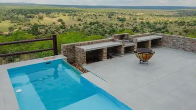 a swimming pool on top of a patio with a view at Pezulu Lodge in Warmbaths