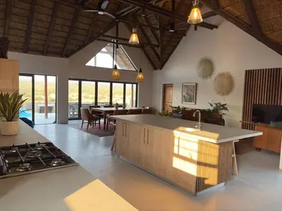a kitchen and living room with a counter and a stove at Pezulu Lodge in Warmbaths