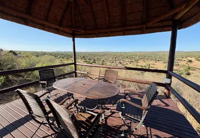 a table and chairs on a deck with a view at Pezulu Lodge in Warmbaths