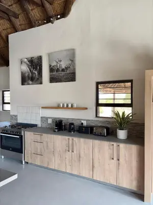 a kitchen with white walls and a wooden counter top at Pezulu Lodge in Warmbaths