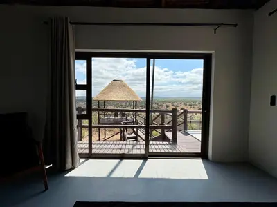 a room with a door open to a deck with a view at Pezulu Lodge in Warmbaths