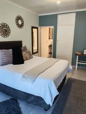 a bedroom with a large white bed with blue walls at Be Our Guest Near OR Tambo International Airport 2 in Boksburg