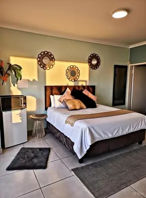 a bedroom with a large bed and a refrigerator at Be Our Guest Near OR Tambo International Airport 2 in Boksburg
