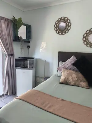 a bedroom with a bed and a kitchen in it at Be Our Guest Near OR Tambo International Airport 2 in Boksburg